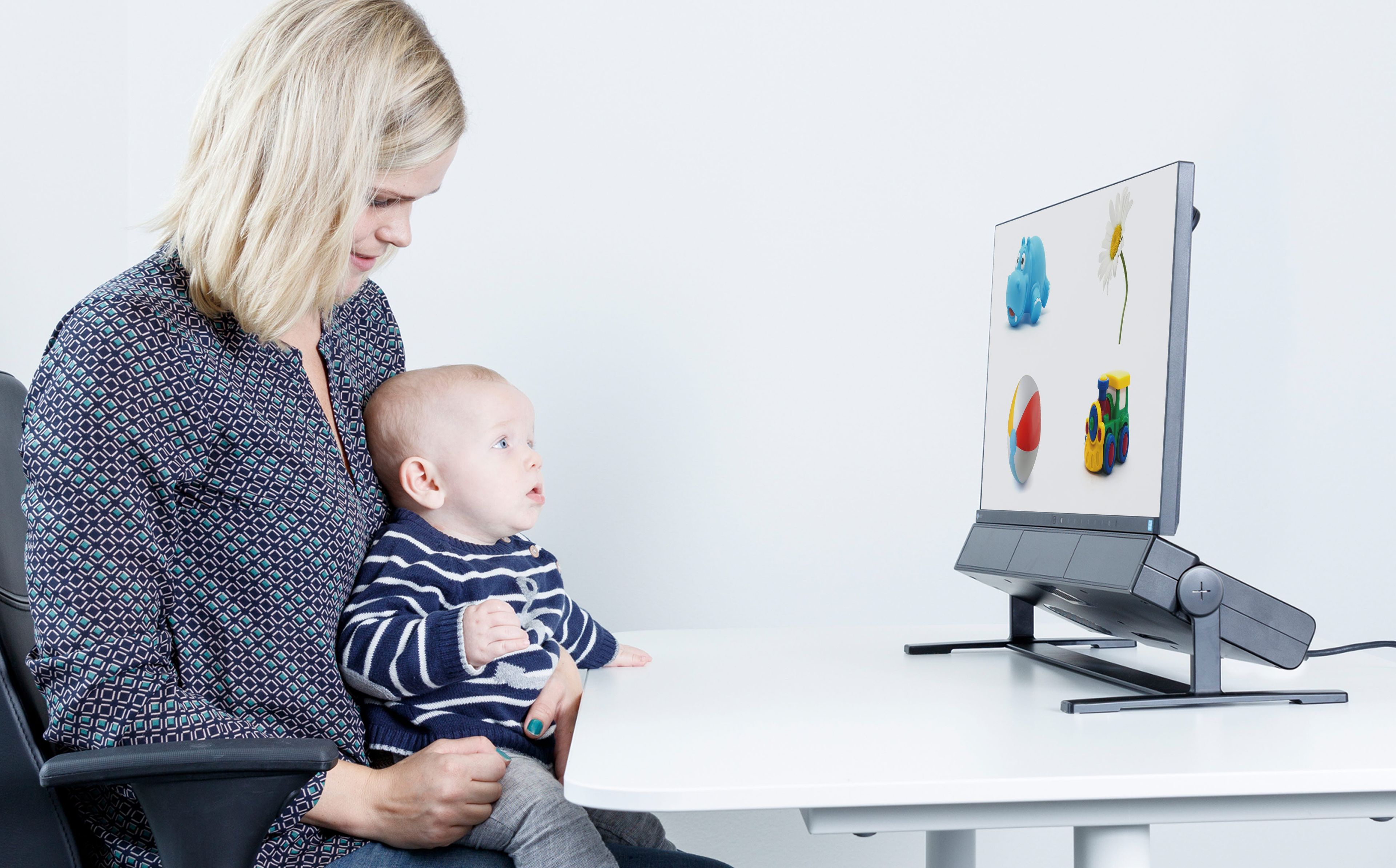 Woman holding a baby using an eye tracker for child development