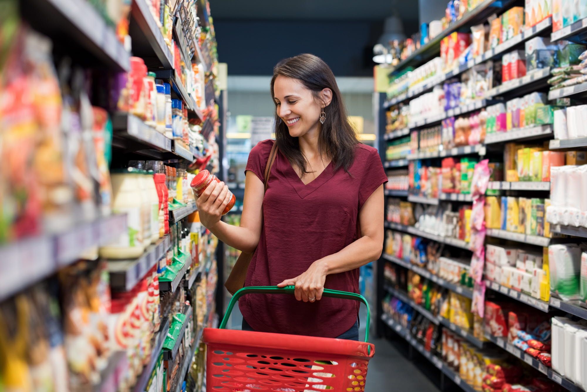 A woman is shopping with a shopping cart.