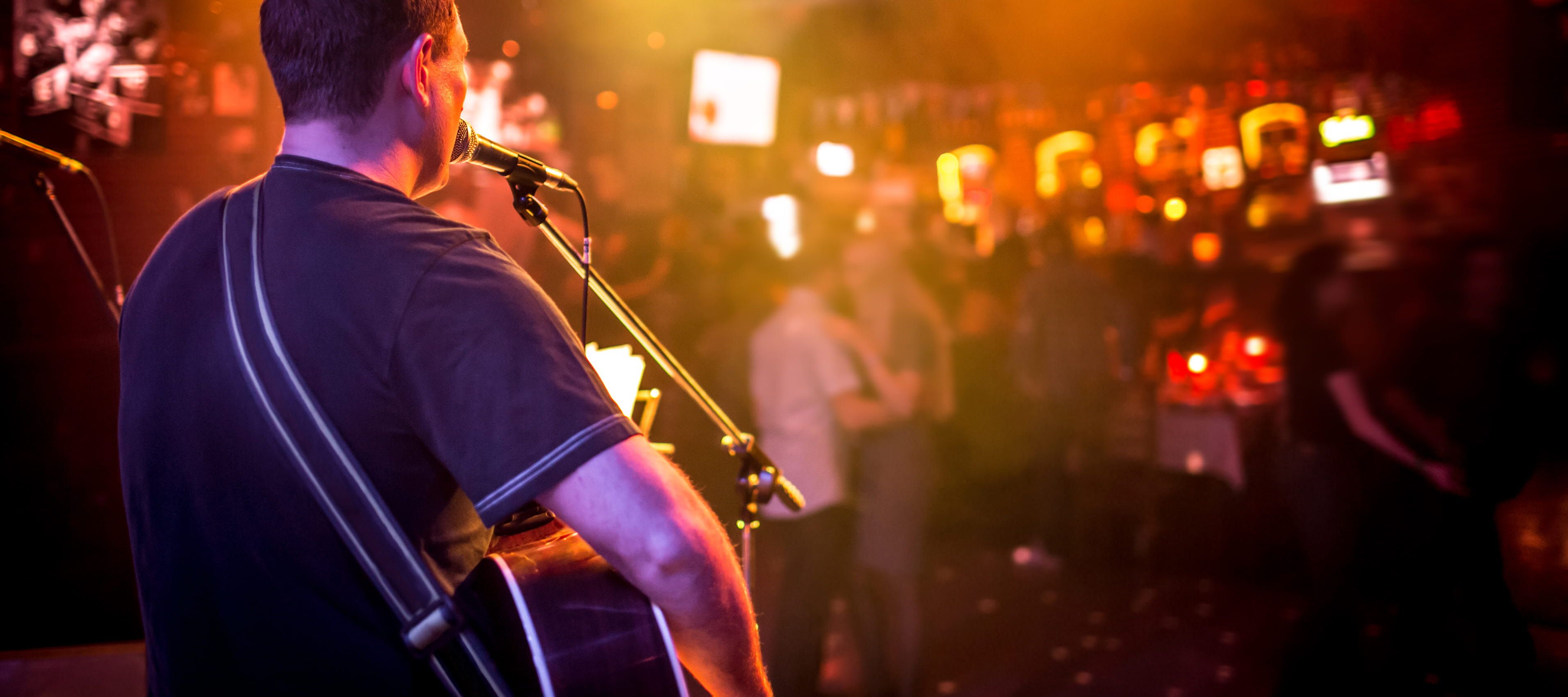 Persom singing and playing the guitar on stage