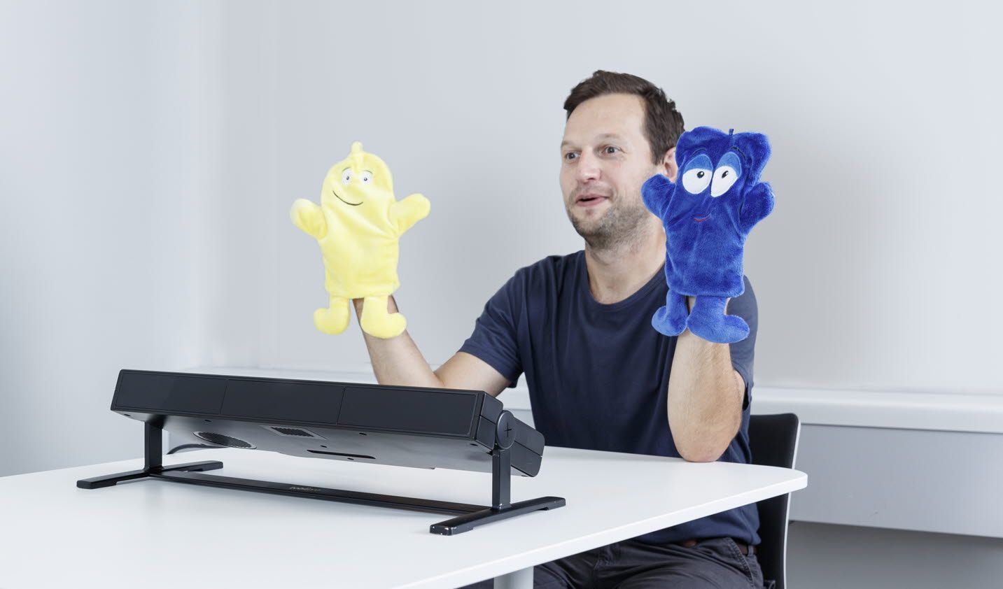 An infant in front of Tobii Pro Spectrum eye tracker looks at a researcher with poppets 