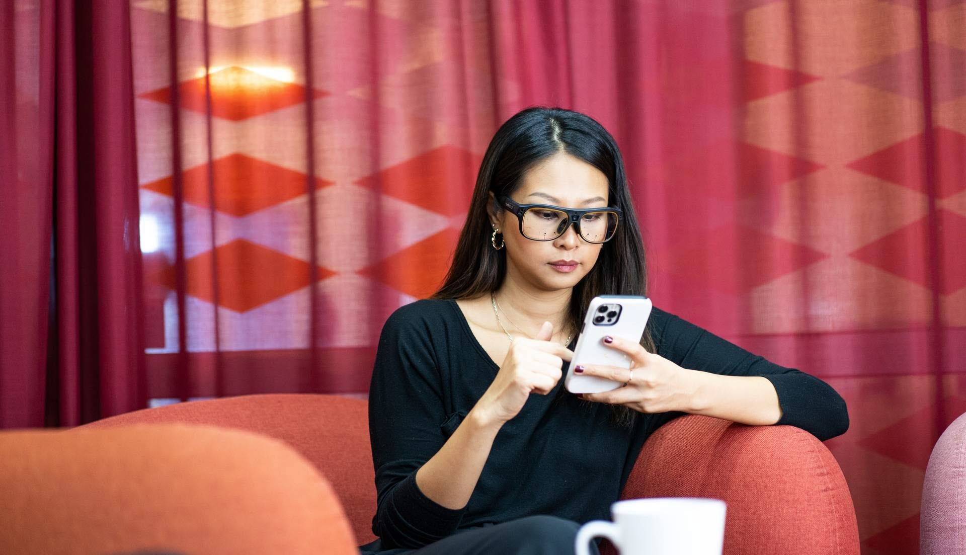 Woman using Tobii Pro Glasses 3 looking at mobile phone