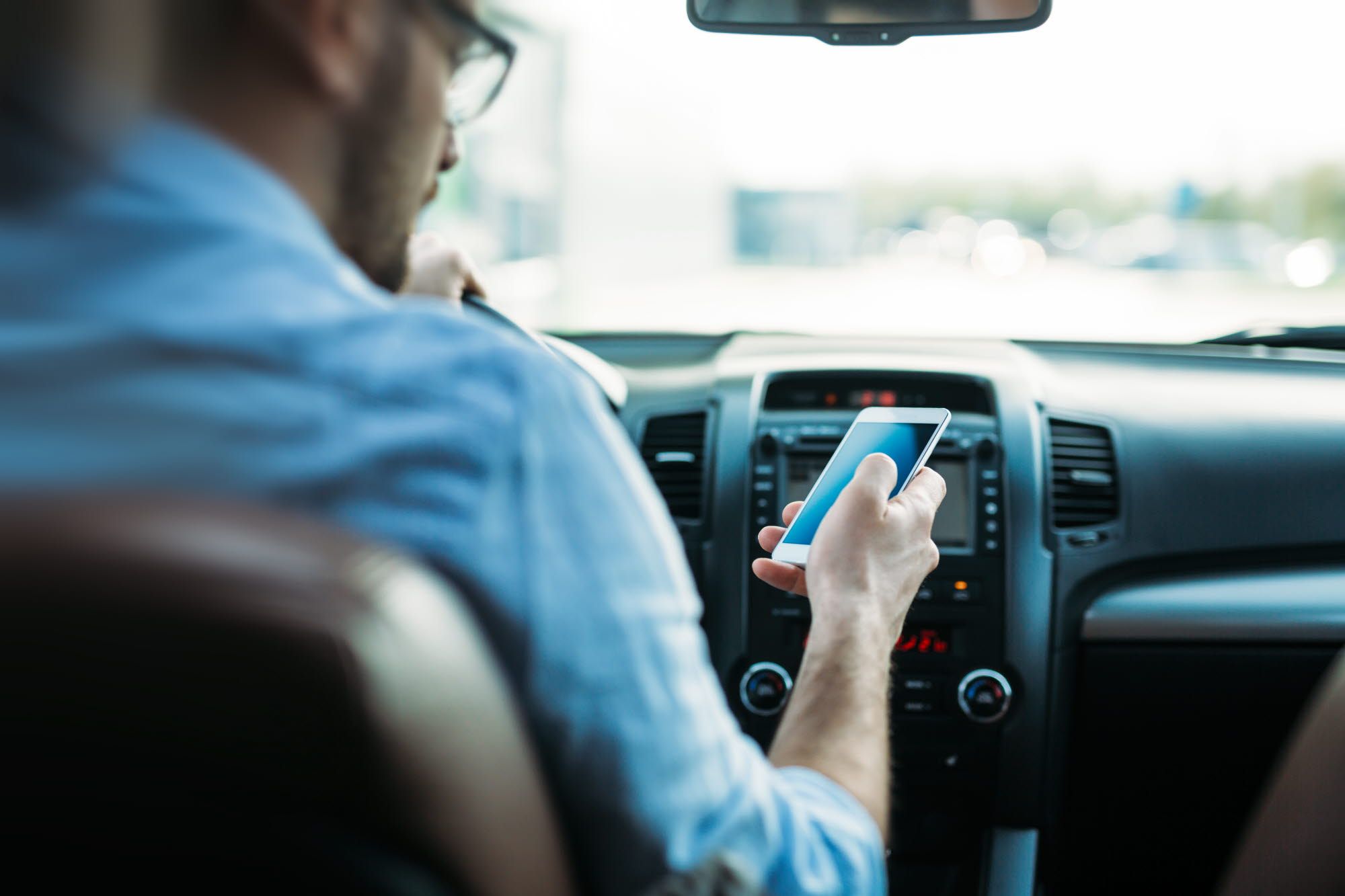 man driving while looking at mobile