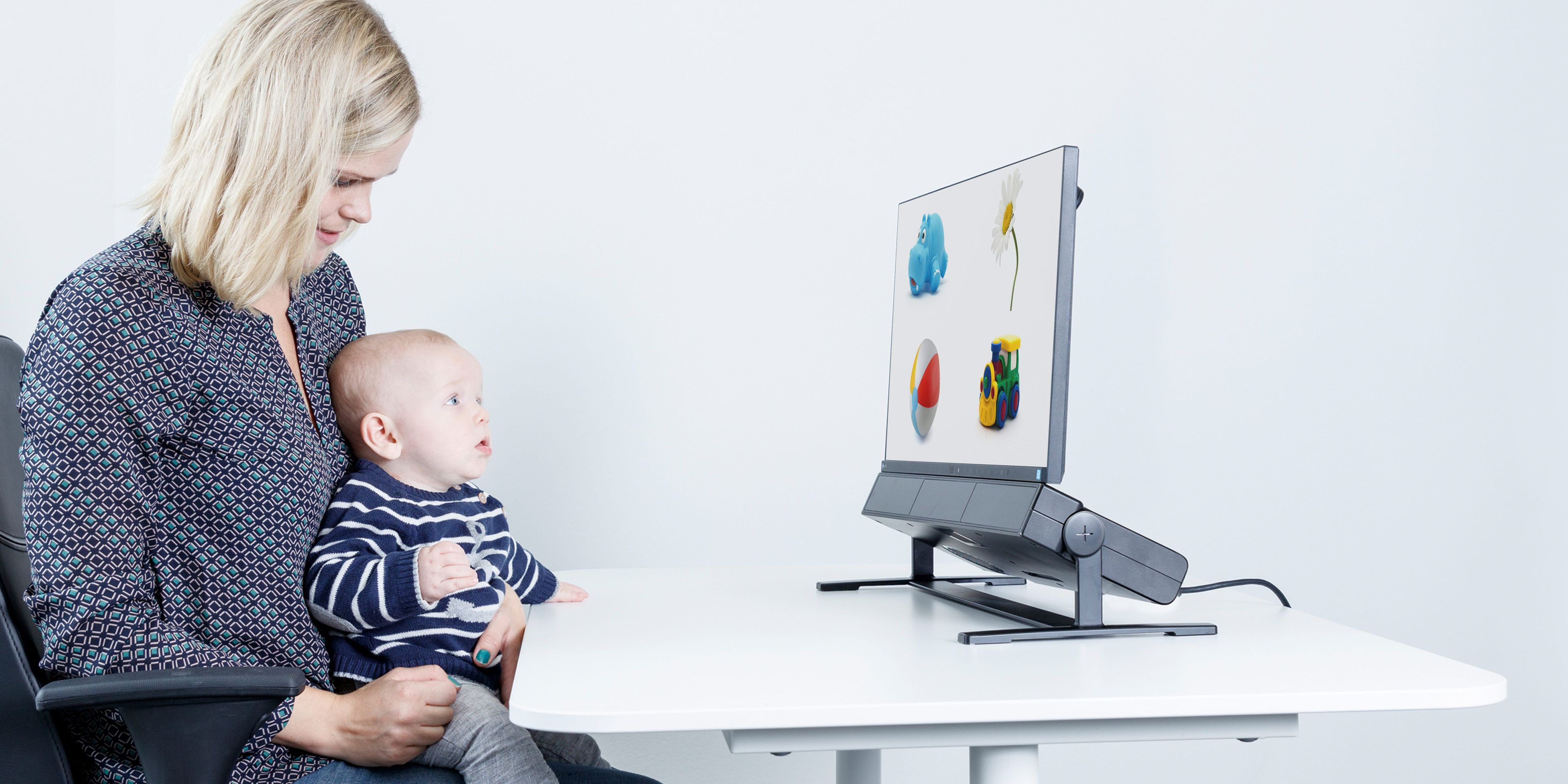 Woman holding a baby using an eye tracker for child development